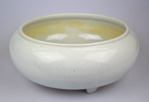 A Chinese white glazed bowl on three short legs incised