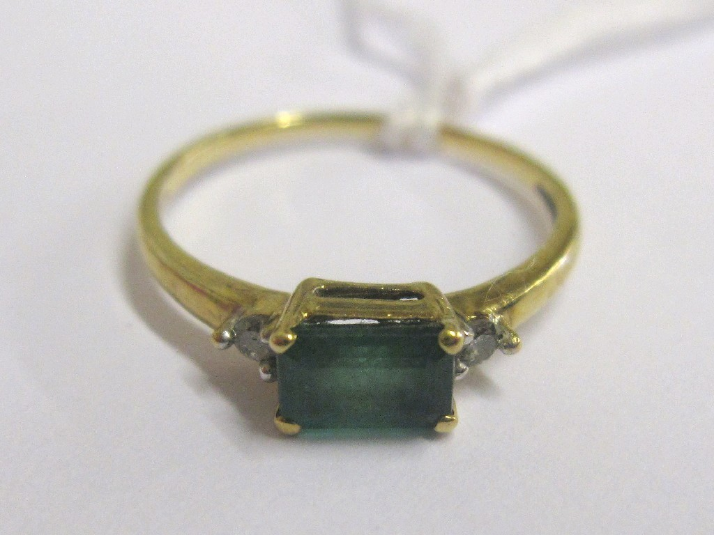 Gold step cut emerald ring with diamond set shouders
