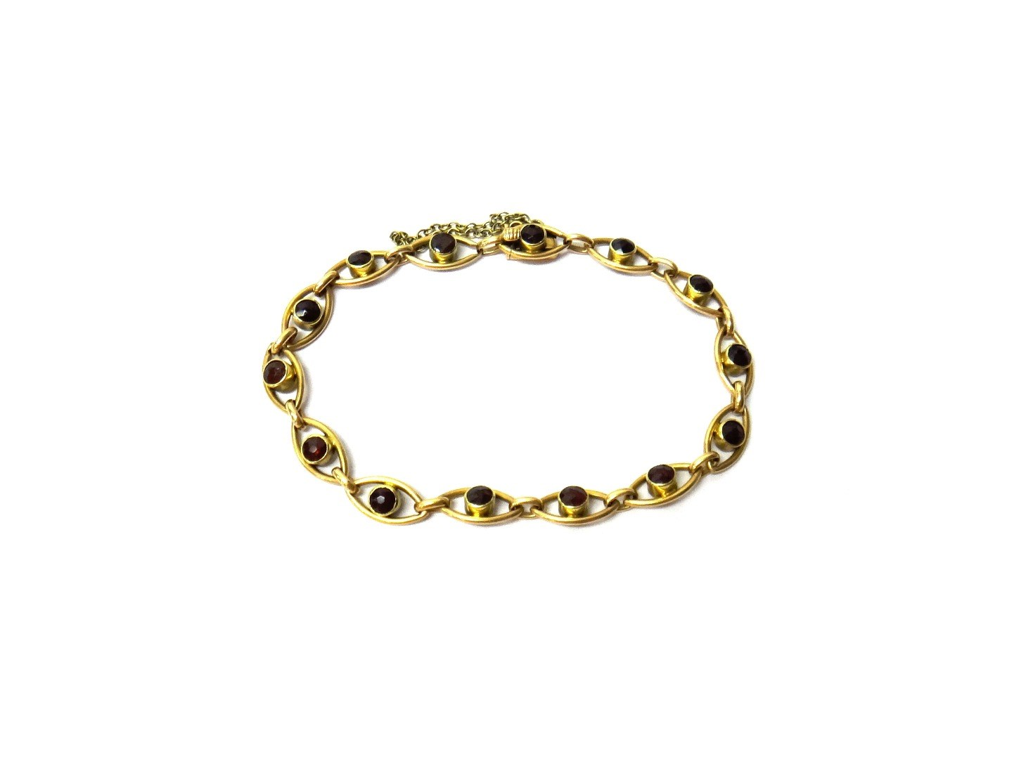 A gold and garnet set bracelet in an oval openwork
