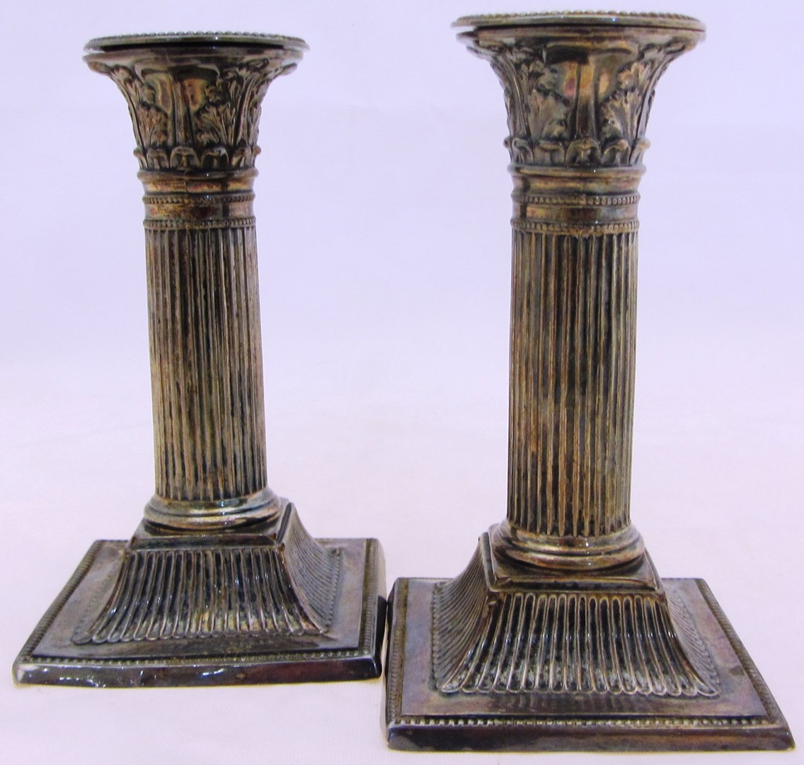 A pair of silver candlesticks each designed as a classical