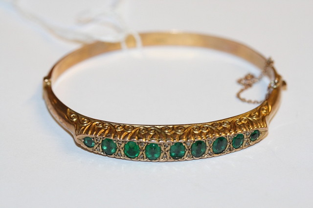 AN EDWARDIAN 9CT GOLD HINGED BANGLE bead set with nine