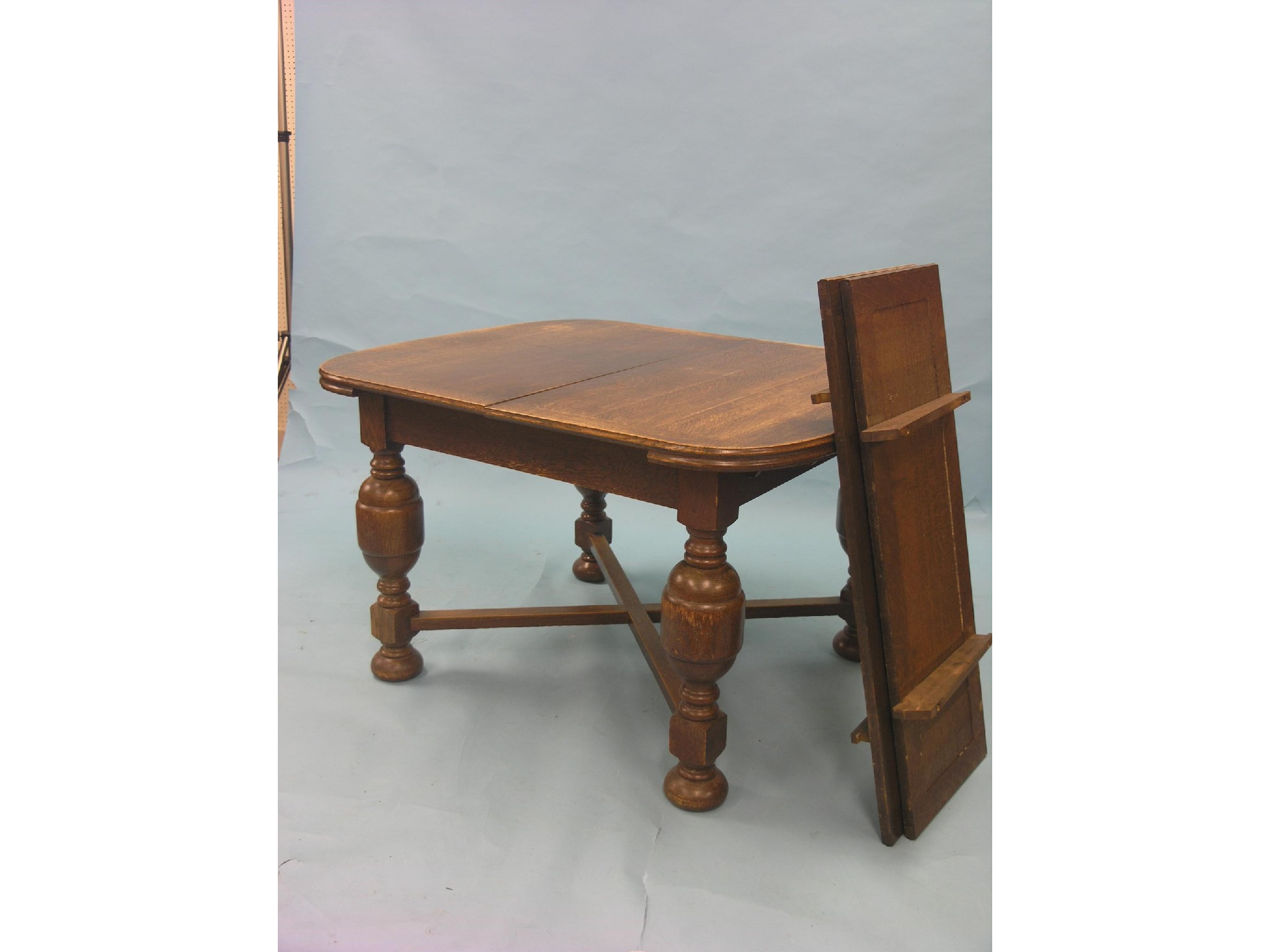 A solid medium oak draw leaf dining table with two