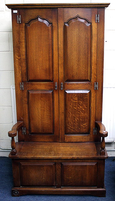 A 20TH CENTURY HARROD S OAK SETTLE HALL CUPBOARD with