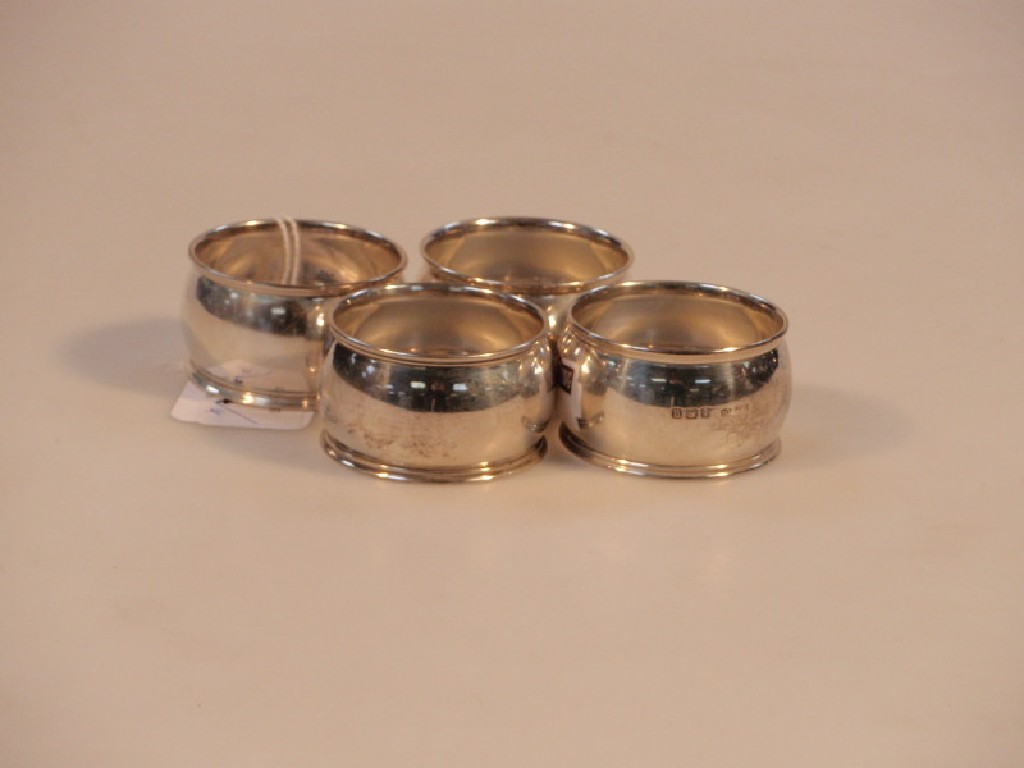 A set of four silver napkin rings of circular cushion