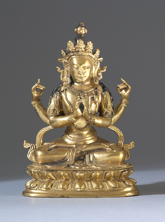 GILT BRONZE FIGURE Depicting a seated four armed deity on