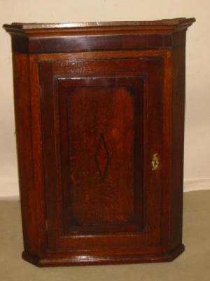 A GEORGE III OAK CORNER CUPBOARD with mahogany banding moulded